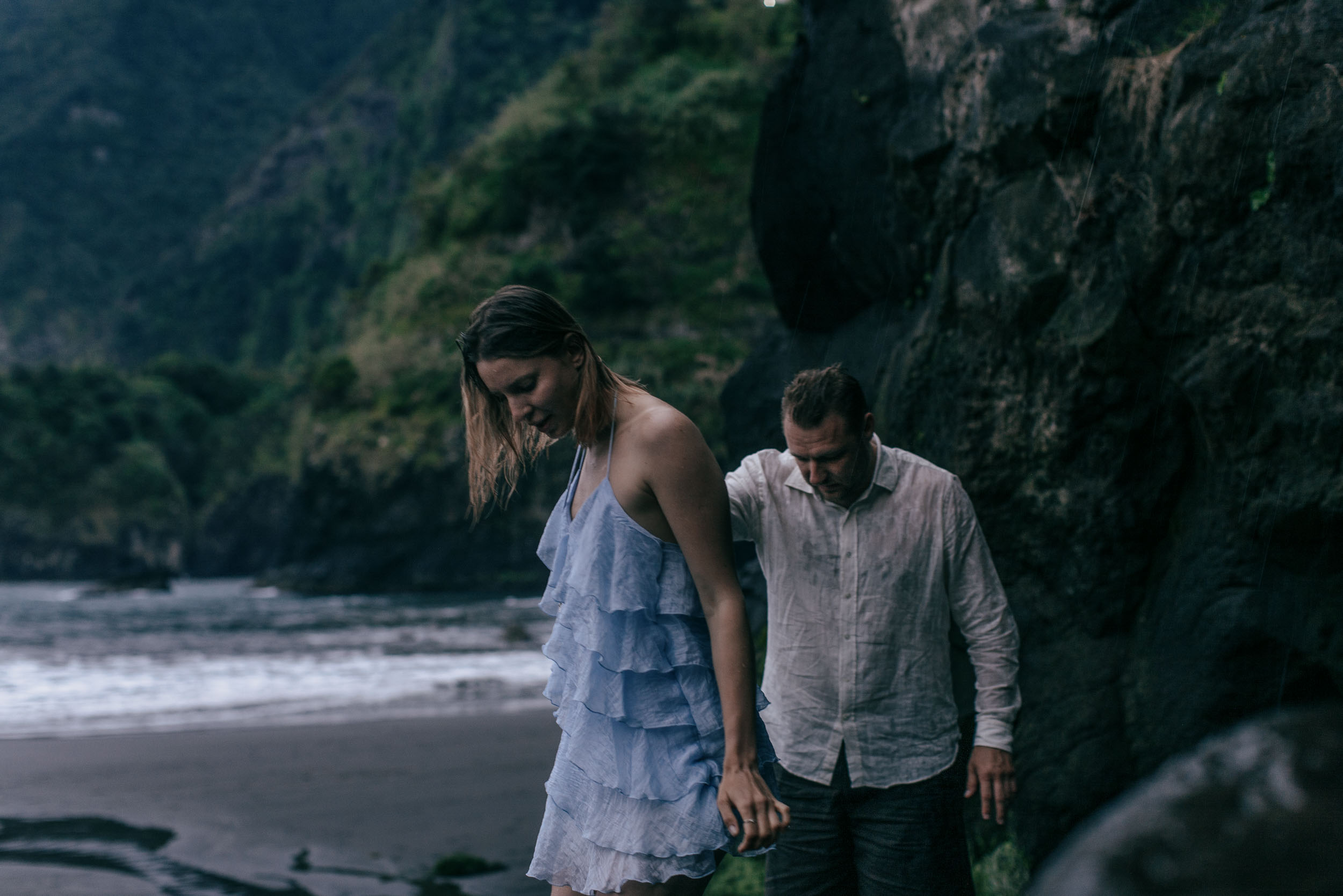 Couple framed by towering volcanic rocks on a dark beach, north Madeira coast