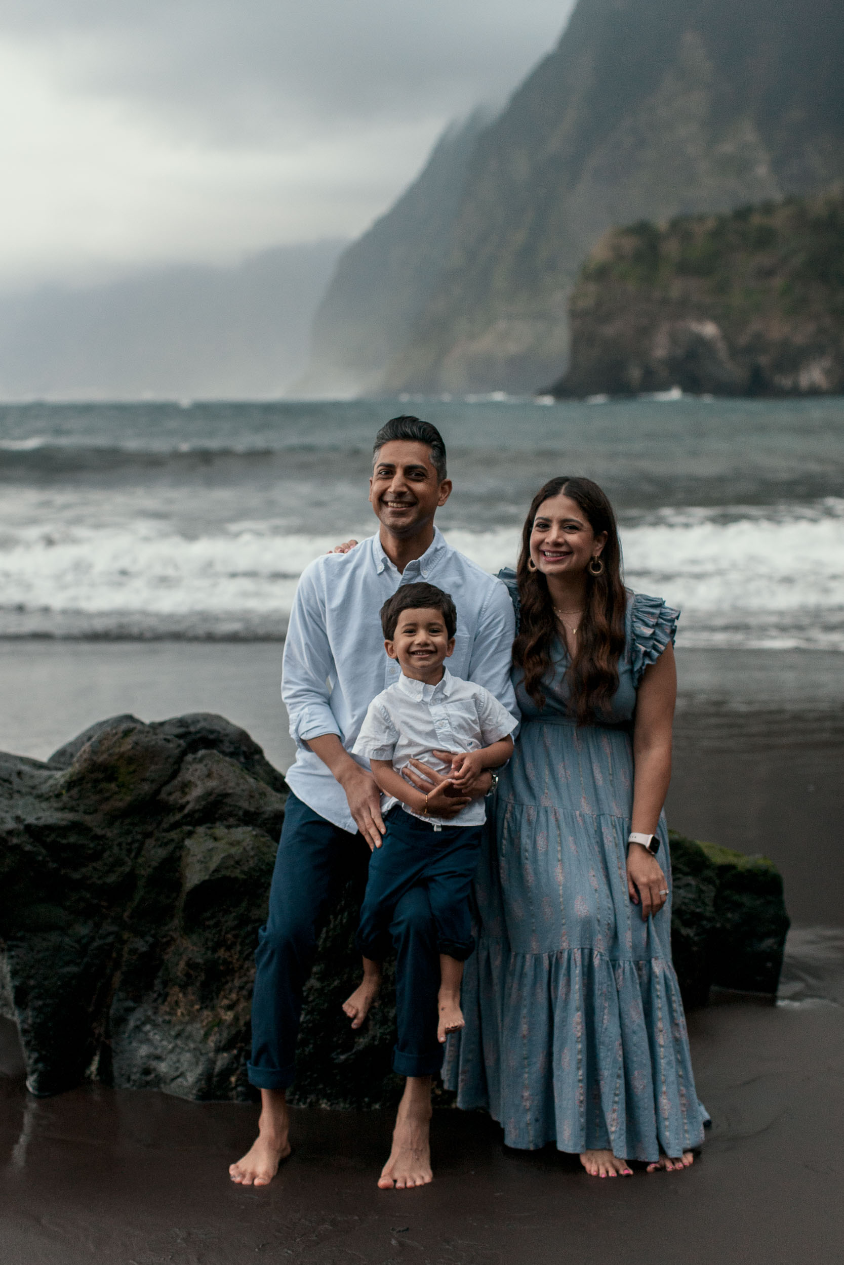 Family portrait by the sea wall at Seixal, Madeira. father holding son, dramatic green cliffs and Atlantic behind