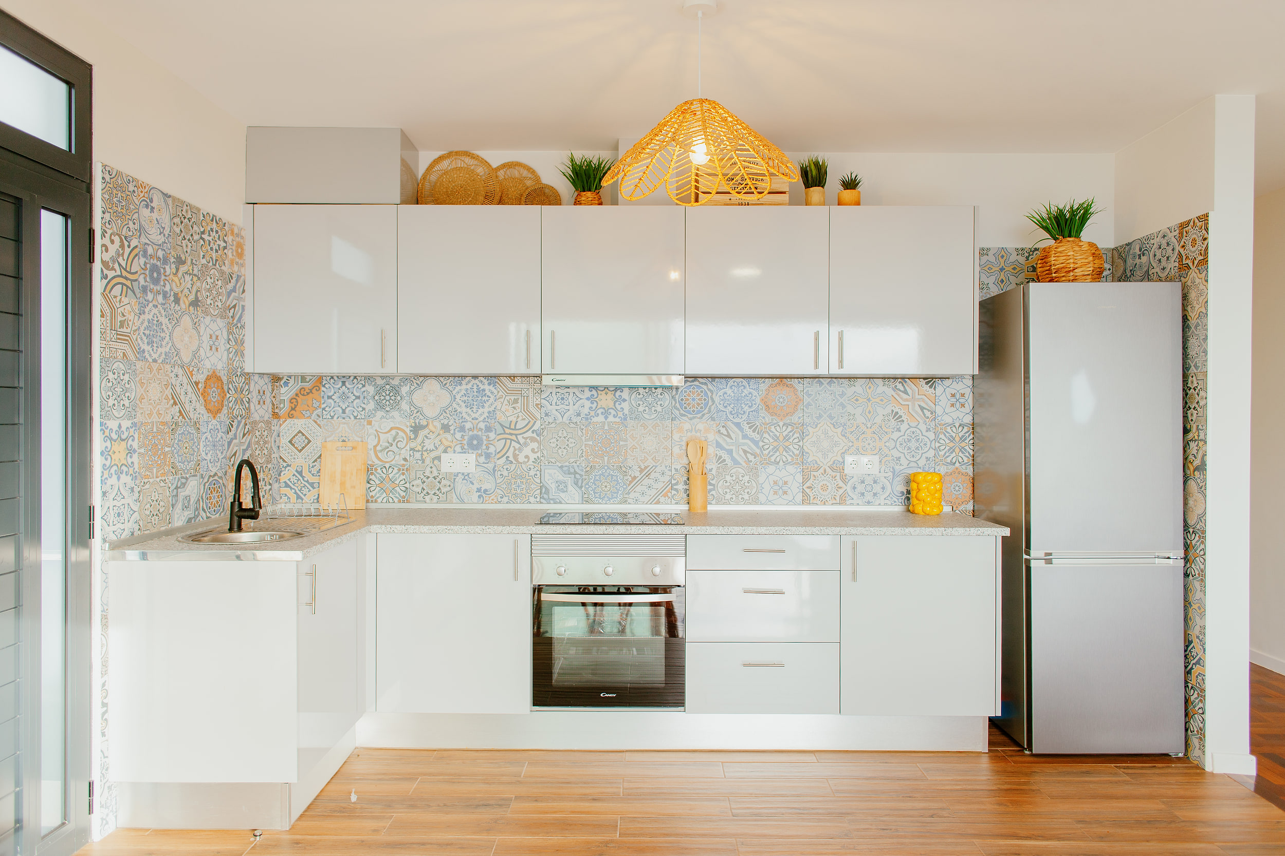White kitchen with a patterned tile splashback, built-in oven and a tall fridge