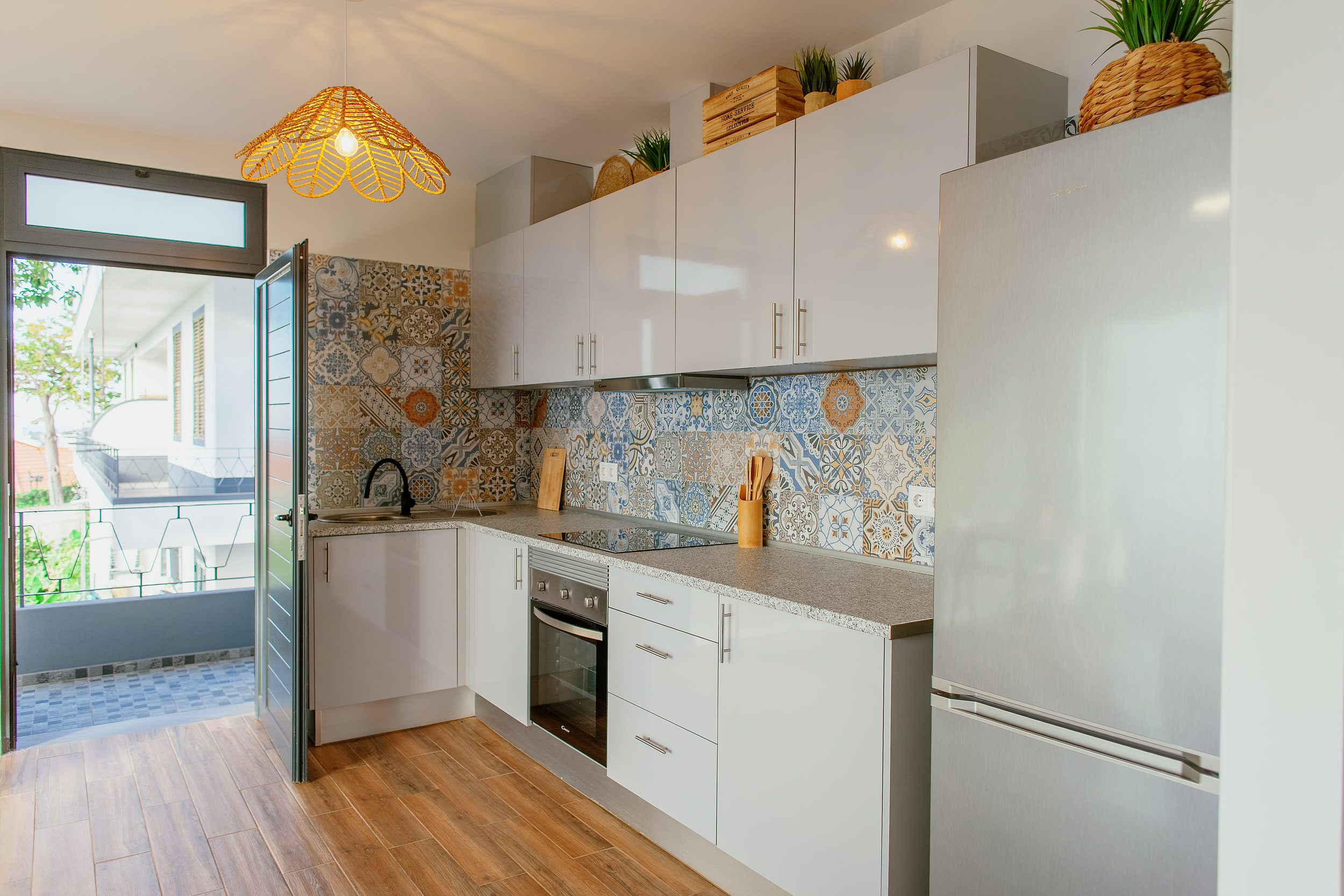Kitchen from the side, the door open to the walkway outside and the wicker lamp lit