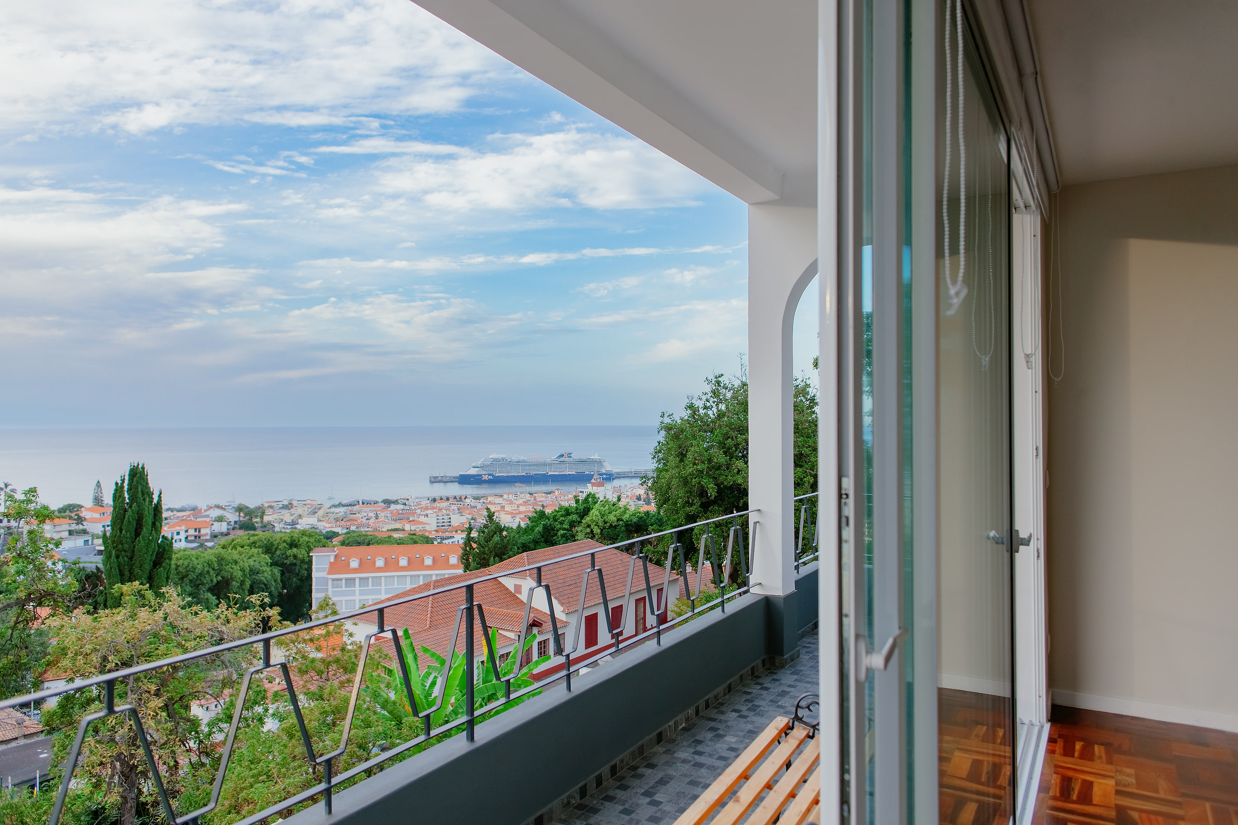 Balcony with a wooden bench, view over Funchal roofs to a cruise ship at the pier
