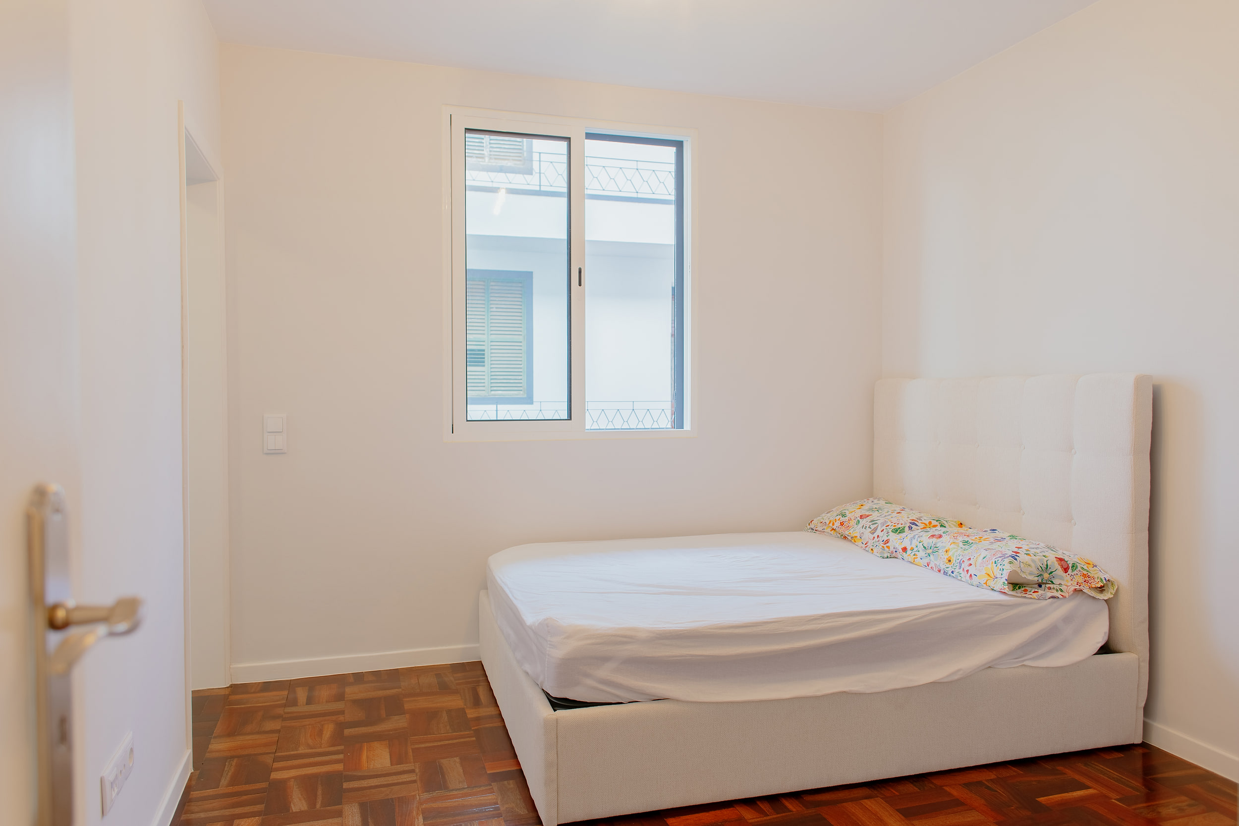 Small bedroom with a white upholstered bed under the window