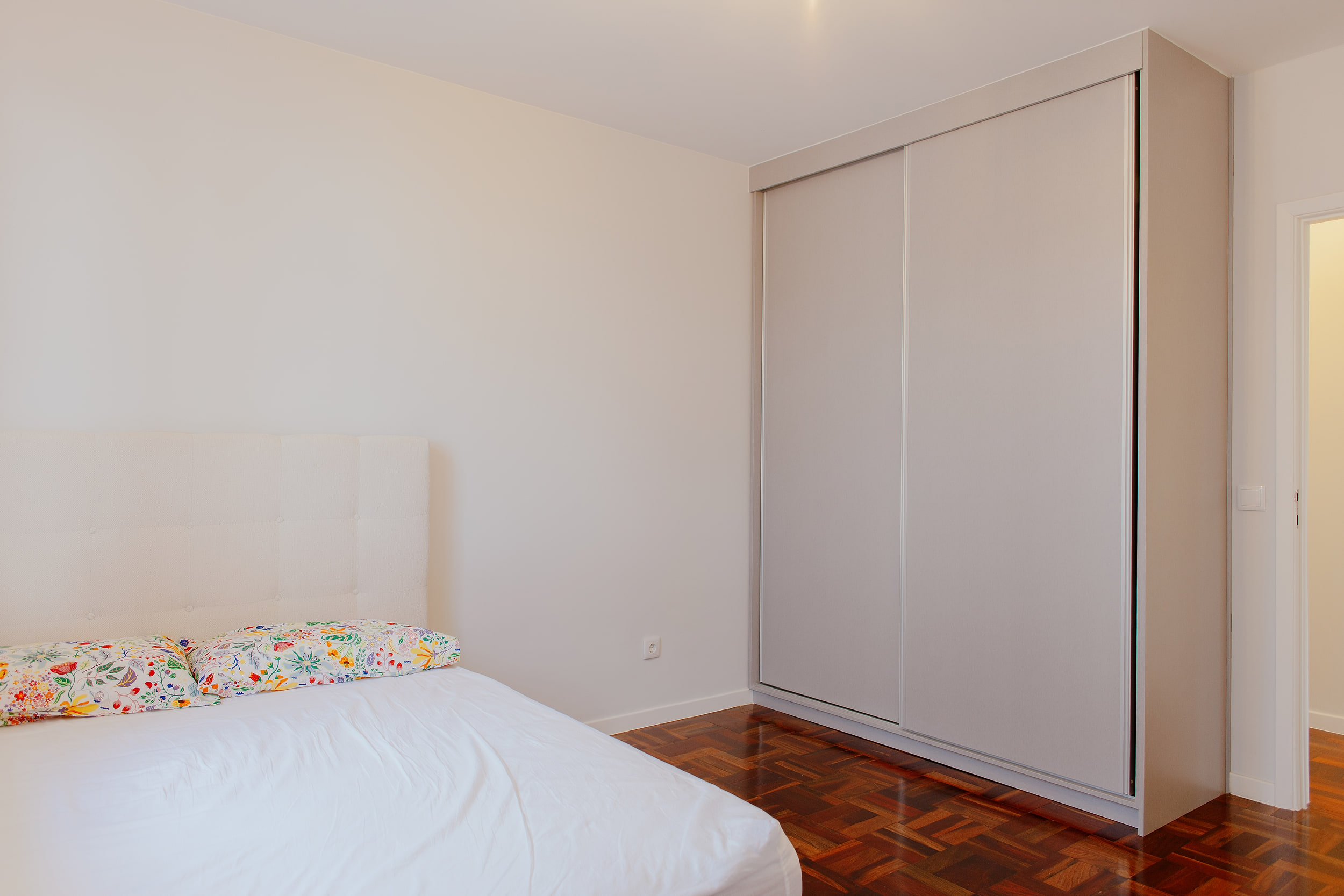 Bedroom corner with a tall built-in wardrobe and parquet floor
