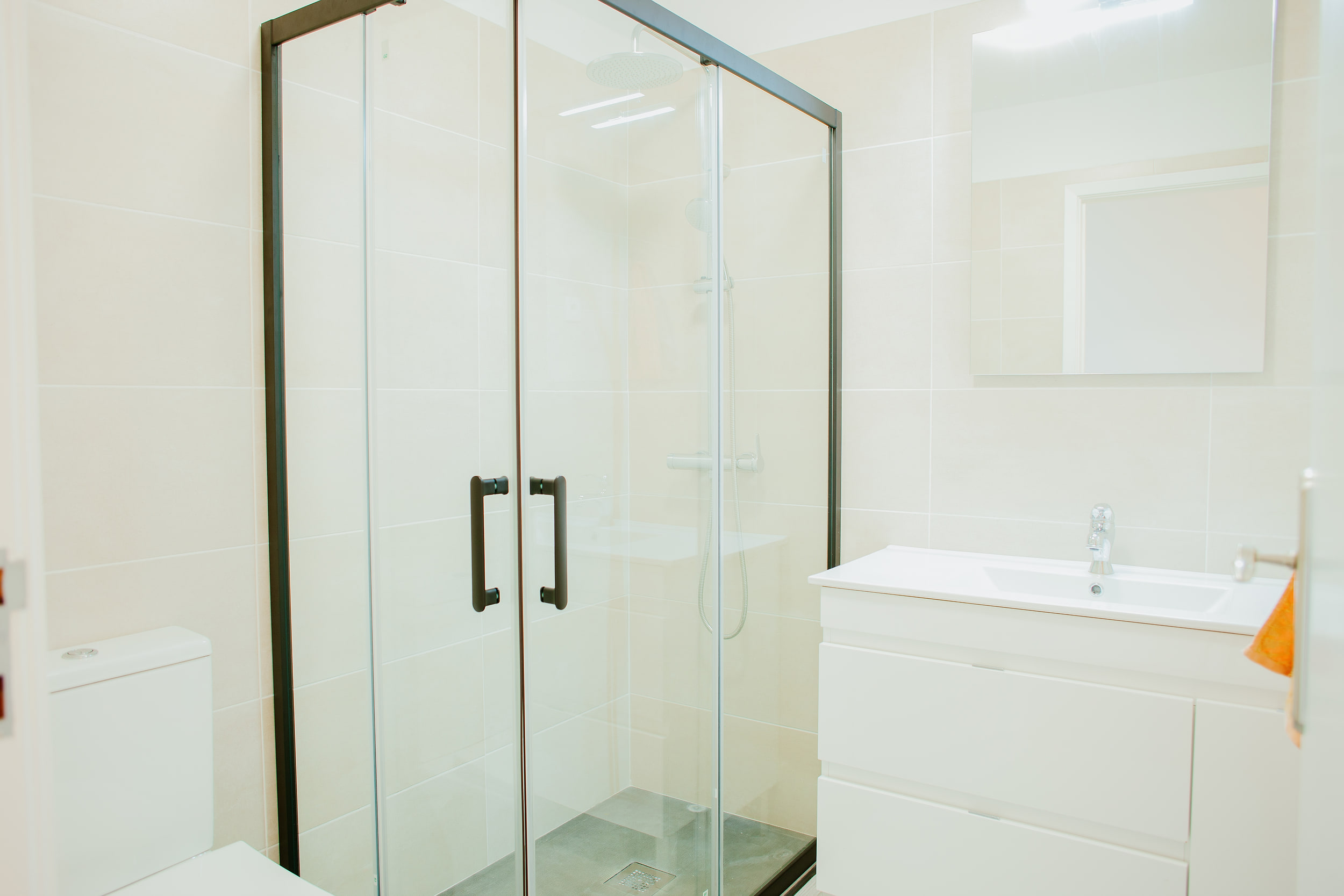 Shower room with a glass enclosure, a white vanity unit and a mirror