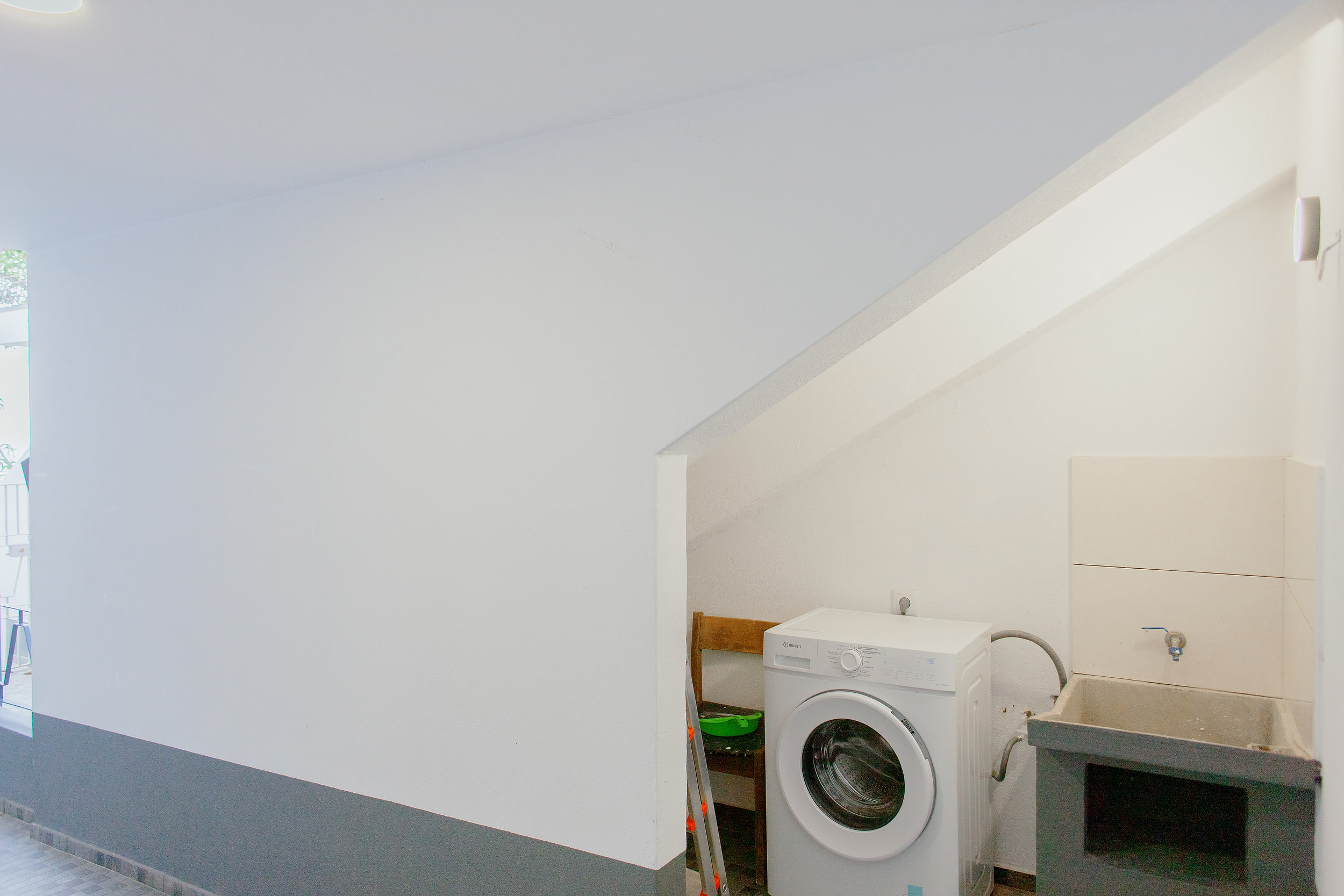 Laundry corner under the stairs with a washing machine and a stone sink
