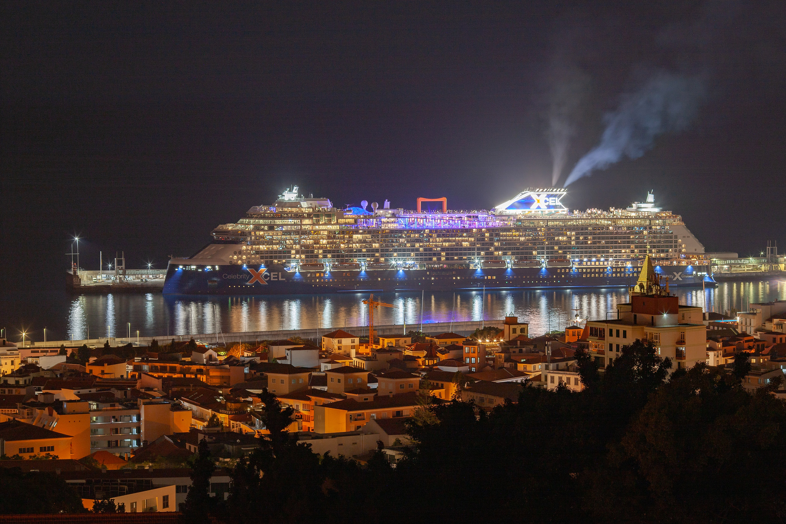 Cruise ship lit up at night in Funchal harbour, the town below