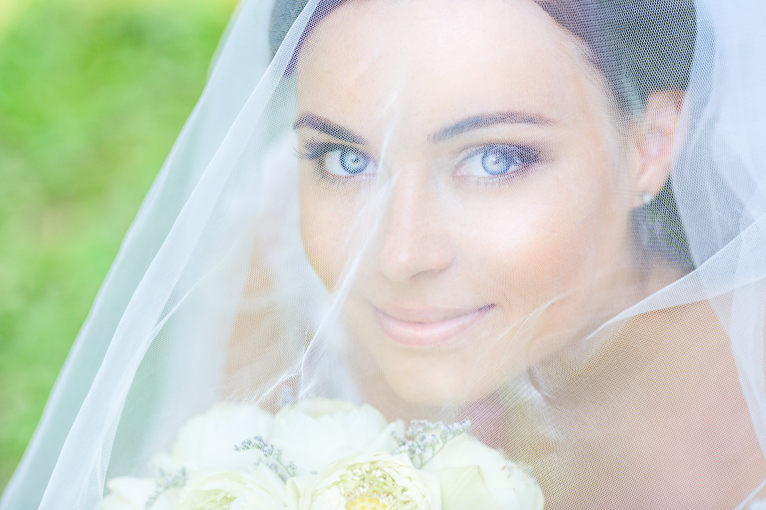 Bride holding her bouquet, face framed by a sheer veil